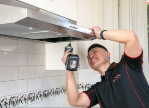 Technician installing kitchen range hood.