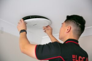 Technician installing ceiling ventilation fan.